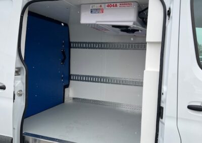 Open white cargo van with side door swung wide, revealing an empty metal-lined cargo area, blue partition on the left, and a mounted 40A box near the ceiling.